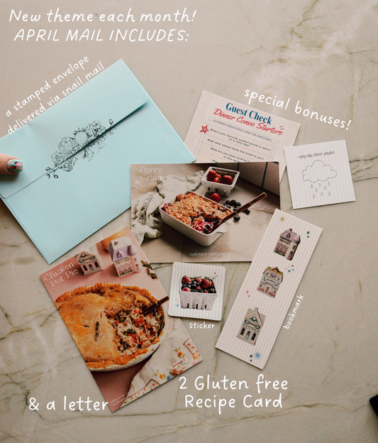 Snail mail club package with blue envelope, recipe cards, and letter on a light gray background

